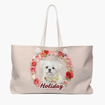 Blush weekender bag printed with a wreath of roses and hearts around a small white dog in a bandana, with "Holiday" below in red script.