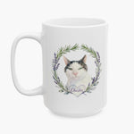 Watercolor portrait of a black and white cat in a rosemary and lavender wreath on the larger white mug, with the name Chester below.