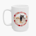 Three cats, one ginger, one gray and one cream, grouped inside a wreath of roses and hearts on the taller 15 oz white mug.