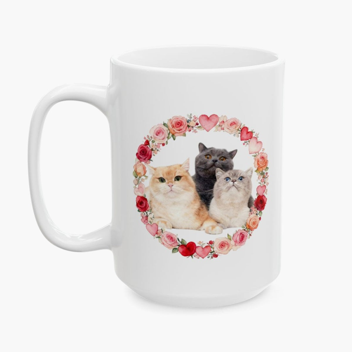 Three cats, one ginger, one gray and one cream, grouped inside a wreath of roses and hearts on the taller 15 oz white mug.