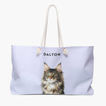 Watercolor portrait of a green-eyed Maine Coon cat on a lavender weekender bag, with the name DALTON printed above.