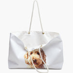 The soft white weekender bag standing open, its white cotton lining and sewn-in care label showing, with the watercolor doodle portrait below.