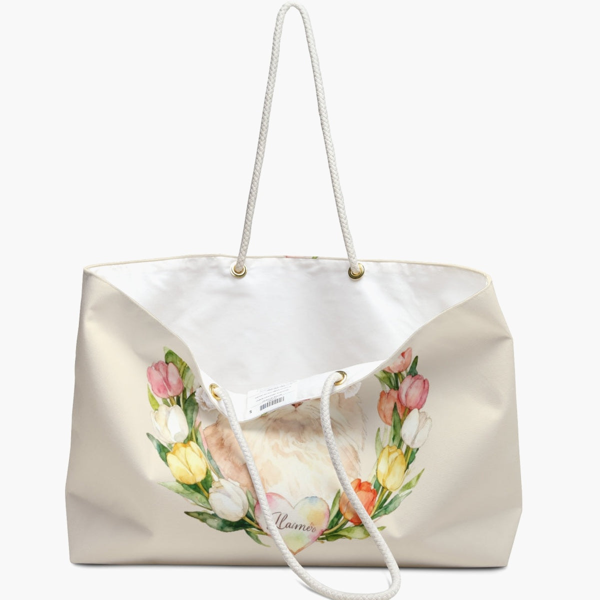 The cream tulip-wreath weekender bag standing open, white lining and care label showing, with the Persian cat and its name heart below.