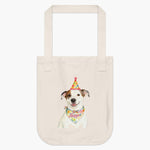 Natural cotton tote bag printed with a watercolor white and tan dog in a polka-dot party hat, wearing a bandana that reads "Hopper".