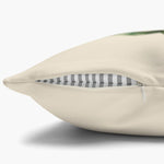 Close-up of the cream pillow cover's edge with the concealed zipper open, showing the gray striped insert and woven fabric.