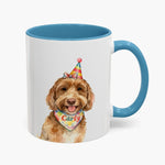Watercolor brown labradoodle in a rainbow party hat on an 11 oz white mug with a light blue handle, the name Carly on its bandana.