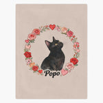 Beige fleece blanket printed with a black cat looking up, framed by a ring of watercolor roses and hearts, with the name "Popo" below.