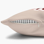 Close-up of the beige pillow cover's edge with the concealed zipper open, showing the gray striped insert and a hint of red art above.
