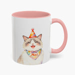 Watercolor fluffy cream cat laughing in a party hat on an 11 oz white mug with a pink handle, the name Mai lettered on its bandana.