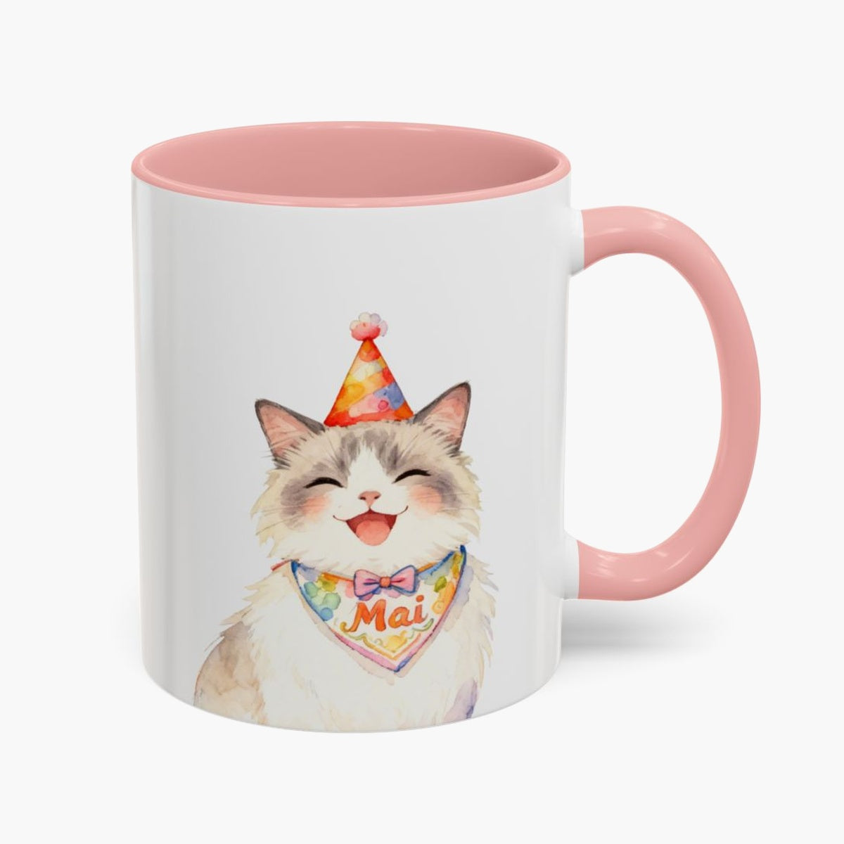 Watercolor fluffy cream cat laughing in a party hat on an 11 oz white mug with a pink handle, the name Mai lettered on its bandana.