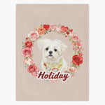 Beige fleece blanket printed with a white Maltese in a patterned bandana inside a ring of roses and hearts, with the name "Holiday" below.