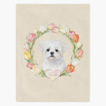 Cream fleece blanket printed with a small white Maltese framed by a ring of watercolor tulips, the pet's name in a pink heart below.