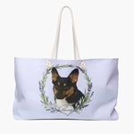 Pale lilac weekender bag printed with a rosemary and lavender wreath around a black and tan shepherd dog, with "Harvey" in script on a heart.