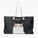 Watercolor portrait of a blue-eyed ragdoll cat on a charcoal gray weekender bag, with the name PRINCESS printed above in white.