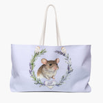 Pale lilac weekender bag printed with a rosemary and lavender wreath around a brown pet mouse, with "Joel Mouse" in script on a heart.