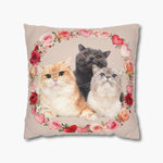 Three watercolor cats, one ginger, one gray and one cream, grouped inside a rose and heart wreath on a beige throw pillow, with no name.