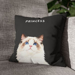 The charcoal gray pillow with the ragdoll cat "PRINCESS" design, angled against a gray woven couch beside a leafy green houseplant.
