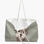 The sage weekender bag standing open, white cotton lining and care label showing, with the watercolor terrier portrait below.