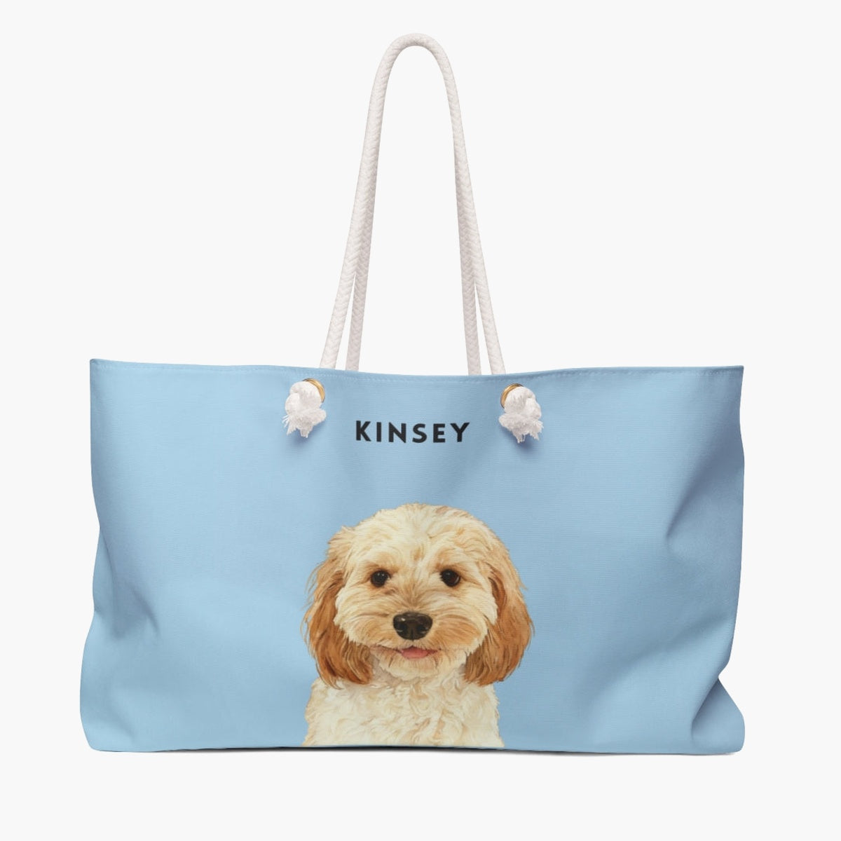 Watercolor portrait of an apricot cavapoo on a French blue weekender bag with white rope handles, with the name KINSEY printed above.