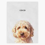 Watercolor portrait of a cream doodle dog printed on a soft white fleece blanket, with the name "COCO" in capitals above.