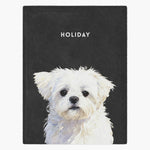 Watercolor portrait of a small white Maltese printed on a charcoal gray fleece blanket, with the name "HOLIDAY" in white capitals above.