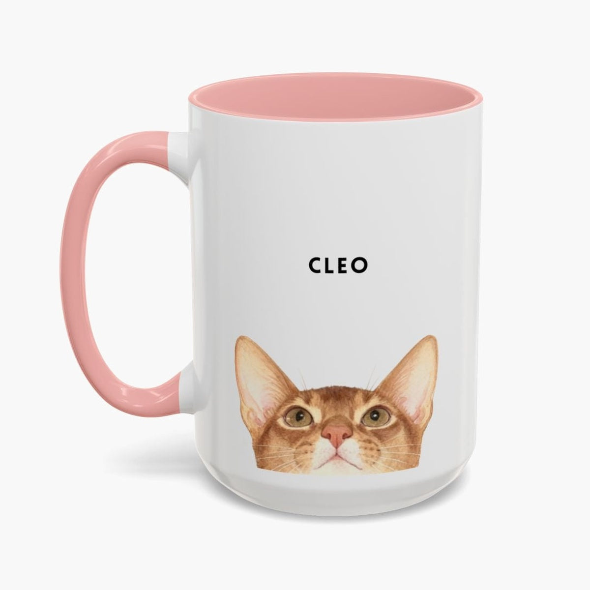 Watercolor ginger cat peeking up over the bottom edge of a taller white 15 oz mug with a pink handle and inner glaze, name "CLEO" above.